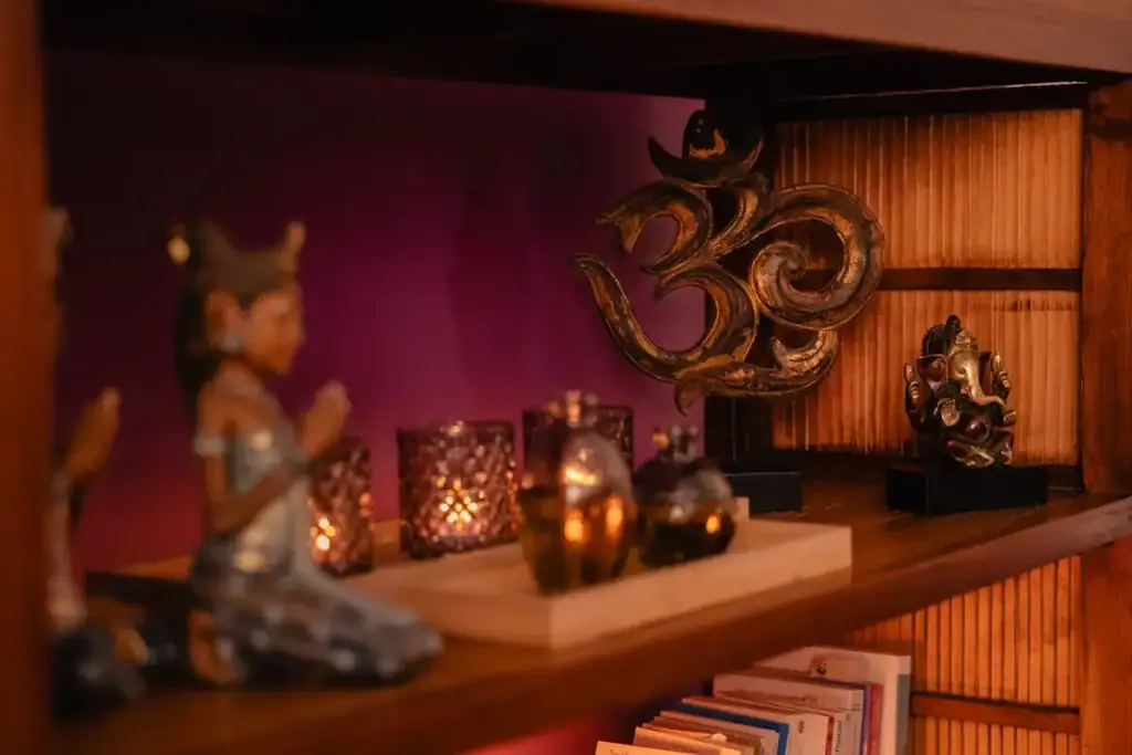 Étagère de décoration du cabinet Koram à Yverdon-les-Bains avec symboles asiatiques, huiles essentielles et livres. Ambiance reflétant le parcours et l'expérience de Stéphane Maillefer en approches globales du bien-être.