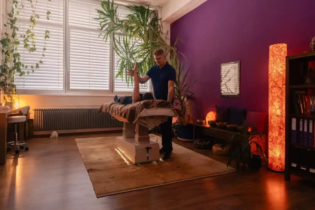Séance de kinésiologie au cabinet Koram à Yverdon-les-Bains : Stéphane Maillefer effectuant un test musculaire sur le bras d'un patient allongé, dans son cadre professionnel.