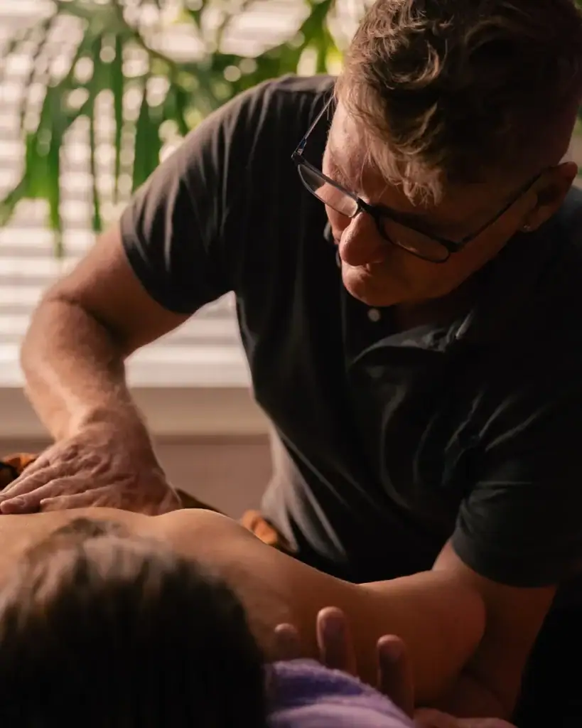 Stéphane Maillefer, masseur à Yverdon-les-Bains, effectuant un massage du dos avec concentration et précision au cabinet Koram. Mains expertes sur les muscles du patient.