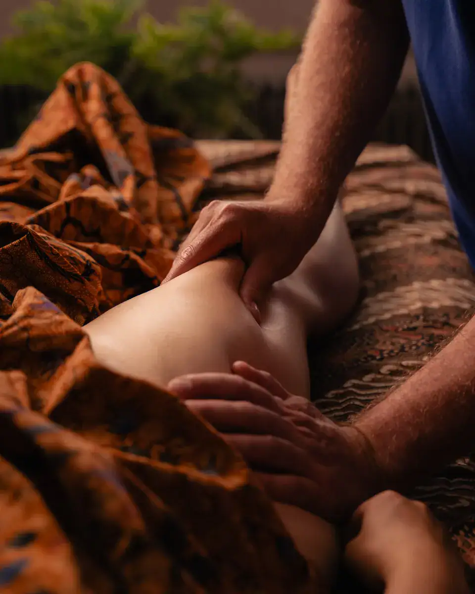 Massage des jambes au cabinet Koram à Yverdon-les-Bains. Stéphane Maillefer effectuant un massage thérapeutique sur les mollets pour favoriser la circulation et la détente musculaire.
